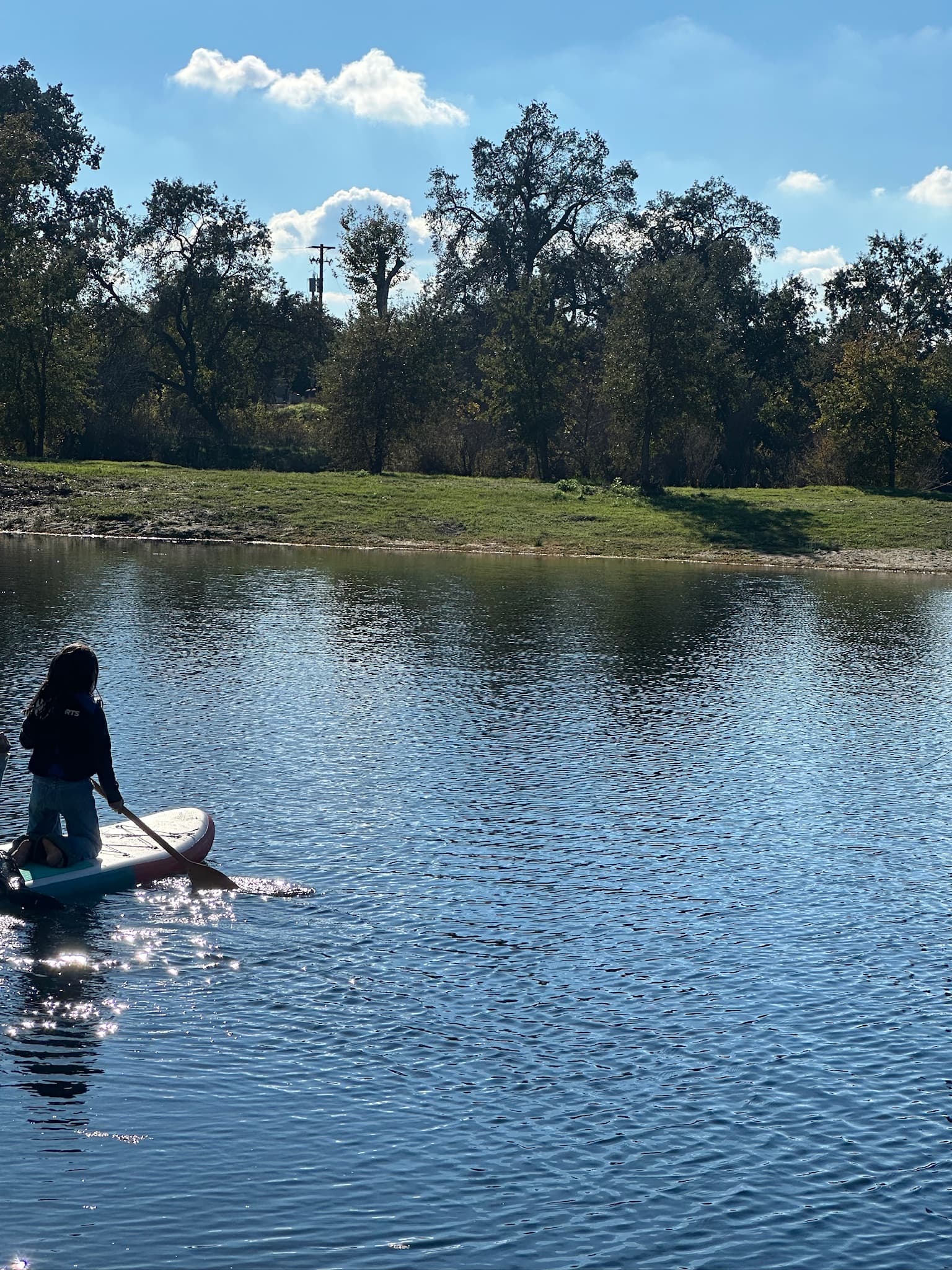 A student paddleboarding across the river